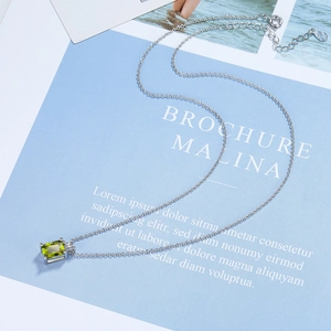 Macro detail of silver emerald-cut olive green zircon pendant on a fine link chain