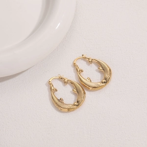Detailed close-up of 14K gold plated hoop earrings with embossed whale carving texture