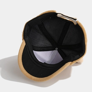 Close-up of the khaki corduroy brim and black inner lining of the baby baseball cap