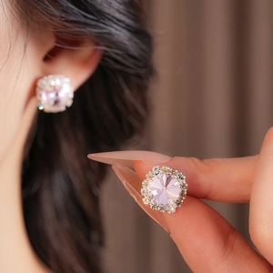 Close-up of pink round diamond earrings with sparkling halo set in silver-tone metal