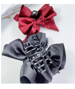 Detailed macro view of large satin bow hair claws in burgundy and black colors