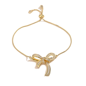 Adjustable gold bow bracelet for women with pavé cubic zirconia on white background