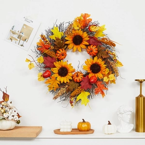 Fall wreath with sunflowers, pumpkins and maple leaves hanging on a white wall