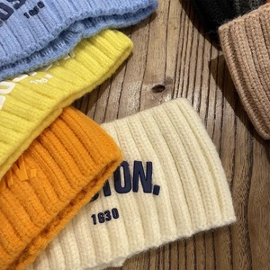 Détail de bandeaux en maille côtelée colorée avec lettrage BOSTON brodé sur bois