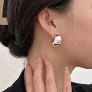 Close-up of thick silver C-shape sterling silver stud earring on female earlobe