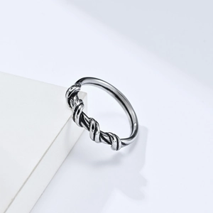 Unisex wire-wrapped silver titanium steel ring with minimalist knotted design on a white prop