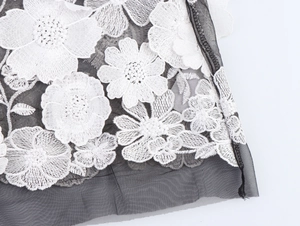 Détail de la broderie florale 3D blanche sur tissu en maille noire transparente