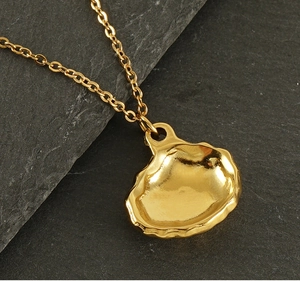 Macro view of gold shell pendant necklace on gray natural rock background