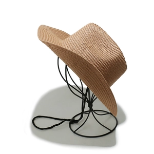Detail of woven straw cowboy hat in tan with adjustable chin strap on a stand