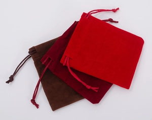 Detailed view of red, wine red and brown velvet drawstring jewelry storage pouches
