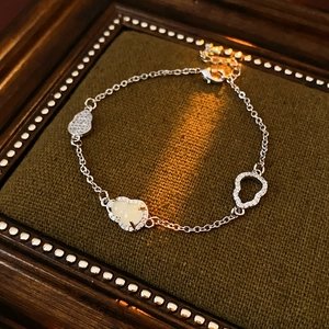 Detail of silver gourd bracelet with pavé zircons and jade-style charms on dark fabric