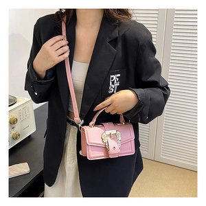 Pink leather handbag with golden T-buckle detail shown on model in a stylish setting