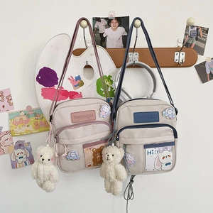 Détail du sac bandoulière en toile avec breloque ours et écussons lapin mignons