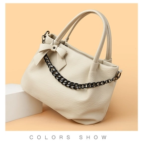Detail view of cream white tote bag with lychee texture and black metal chain link
