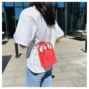Outdoor lifestyle shot of a red crocodile pattern mini bag with golden chain strap