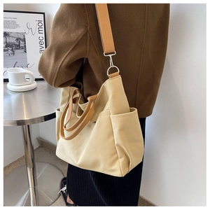 Detail of canvas crossbody bag with orange-brown straps and silver metal buckle