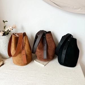 Minimalist matte suede bucket bags in brown and black with wide leather shoulder straps