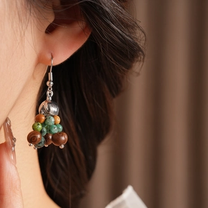 Detail shot of bohemian earrings with turquoise stones and wooden beads on a model