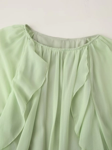 Detailed view of the mint green chiffon dress featuring a ruffled neckline and pleats