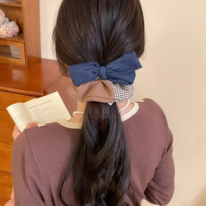 Close-up of navy blue and brown checkered bow scrunchie worn on model hair in warm setting