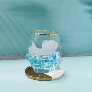 Bicchiere con rilievo a pesce dorato, bordo in oro e base blu oceano elegante