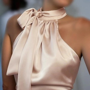 Détail de la robe en satin champagne avec un grand nœud et une texture soyeuse