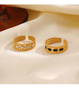 Close-up of 18K gold-plated rings with black and white drip oil on satin background