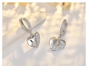 Detail of silver heart hoop earrings with sparkling cubic zirconia on light background