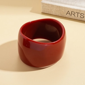 Detail view of a thick vintage red resin bangle with a marbled texture on a soft background