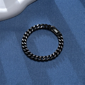 Close-up of black Cuban link bracelet with fold-over clasp on a blue textured surface
