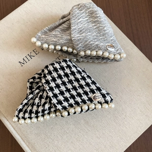 Detail of tweed hair claws with white pearls and engraved metal plates on a book