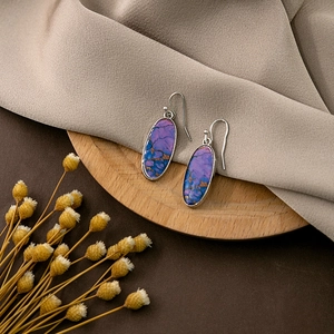 Detail of oval boho earrings featuring purple and blue marble texture with gold accents