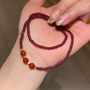 Detail of layered garnet bead bracelet with gold accents held in hand showing texture