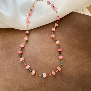 Macro detail of pink crystal beads and colorful seed beads on golden necklace chain