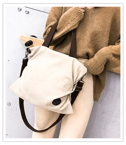 Vue détaillée du sac en toile beige avec bandoulière marron et écusson en cuir