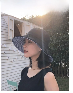 Dettaglio cappello parasole anti-UV a tesa larga con cotone nero e fodera a righe