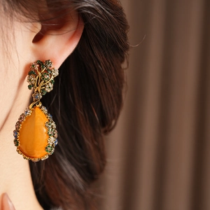 Detailed view of vintage teardrop earrings with amber stones and colorful floral metalwork