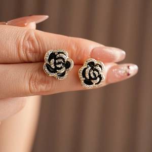 Detailed view of black and gold rose earrings with shimmering crystal accents