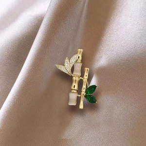Close-up of bamboo brooch with gold metal, opal texture and emerald green leaves