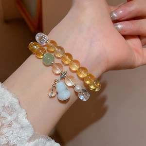 Detail of beaded bracelet set with yellow crystals and a white porcelain gourd pendant