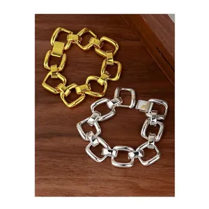 Thick chunky chain bracelet set in gold and silver finish on dark wood surface