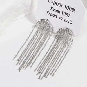 Detail of 18K gold-plated tassel earrings on a textured stone over a white background