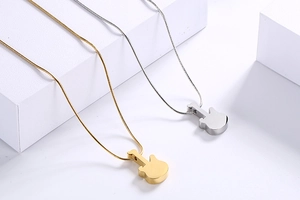 Detailed view of silver and gold guitar pendants with sleek snake chains on white props