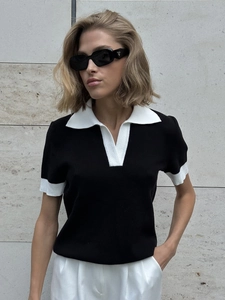 Gros plan sur le col Polo blanc contrasté et la texture tricotée noire du haut d'été