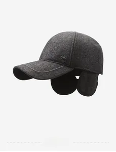 Detail view of winter baseball cap with ear flaps and metal sport emblem in grey