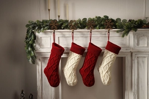 Close-up of red and white cable knit Christmas stockings hanging on a white fireplace