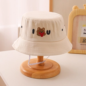 Detail of beige kids bucket hat featuring a teddy bear and IU letter embroidery