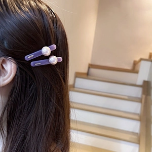 Elegant purple resin hair clip with large white pearl accent worn on long dark hair