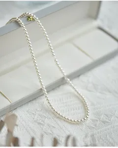 Macro shot of round white pearl necklace with gold clasp on lace background