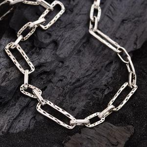 Silver paperclip chain necklace with textured rectangular links on charcoal background